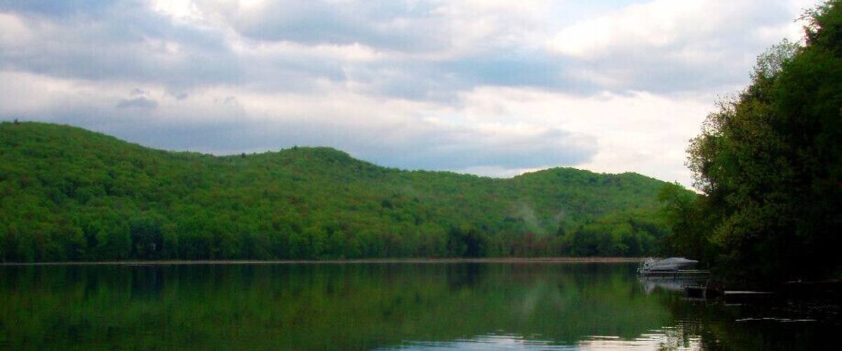 A calm lake with a forested hill in the background and a dock on the right.