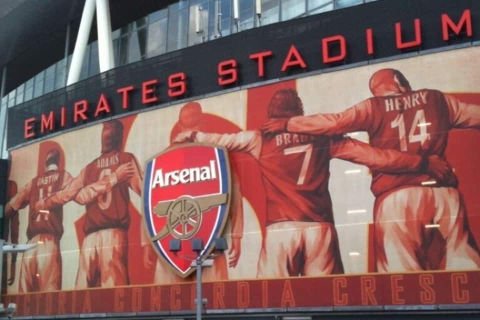 Estadio Emirates con un gran mural de jugadores del Arsenal y el nombre del estadio.