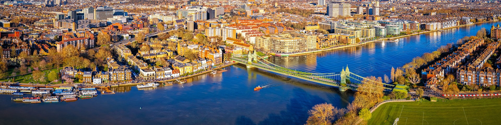 A river with a bridge, a cityscape with historic buildings, and a green park area.
