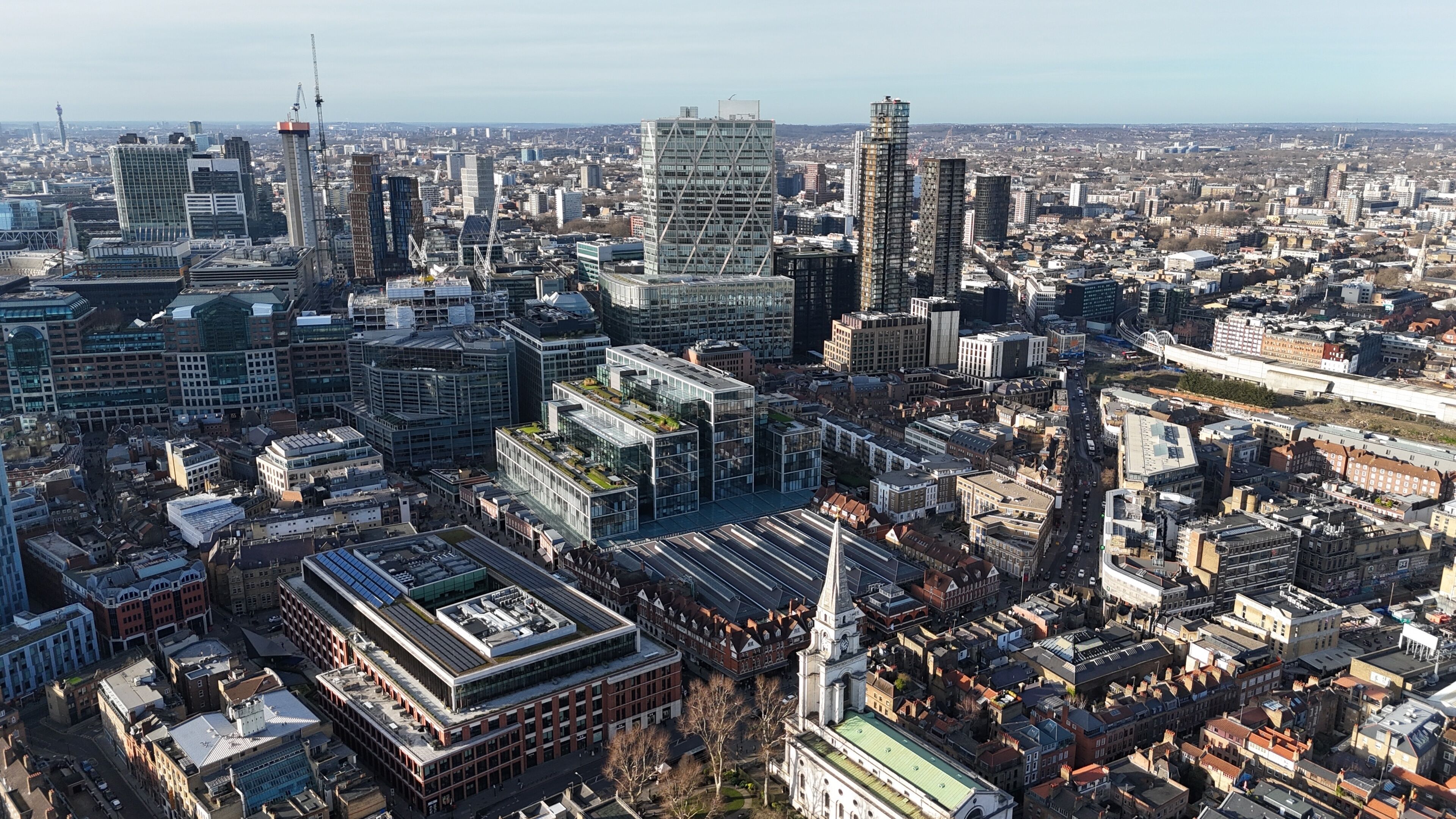 A dense urban landscape with a mix of modern and historic architecture, including a prominent clock tower.
