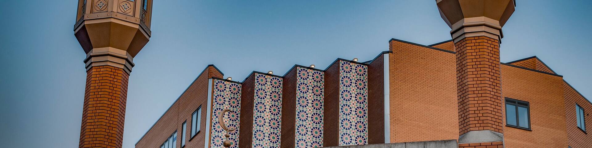 The East London Mosque with two minarets and a tiled facade.