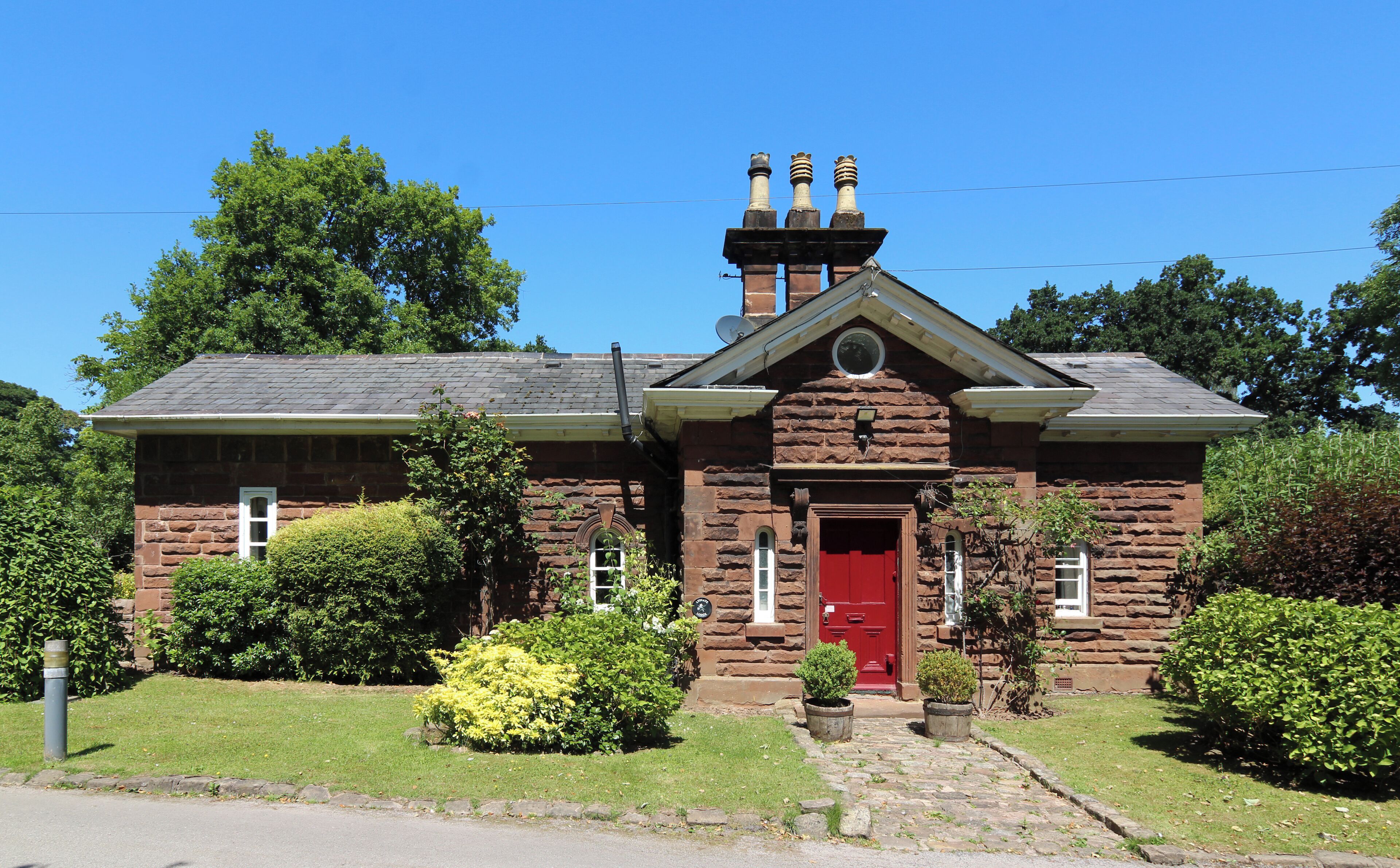 A stone house with a red door, chimney, and satellite dish.