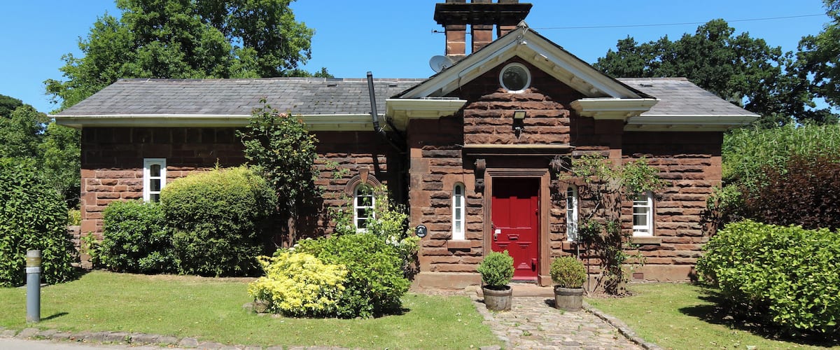 A stone house with a red door, chimney, and satellite dish.