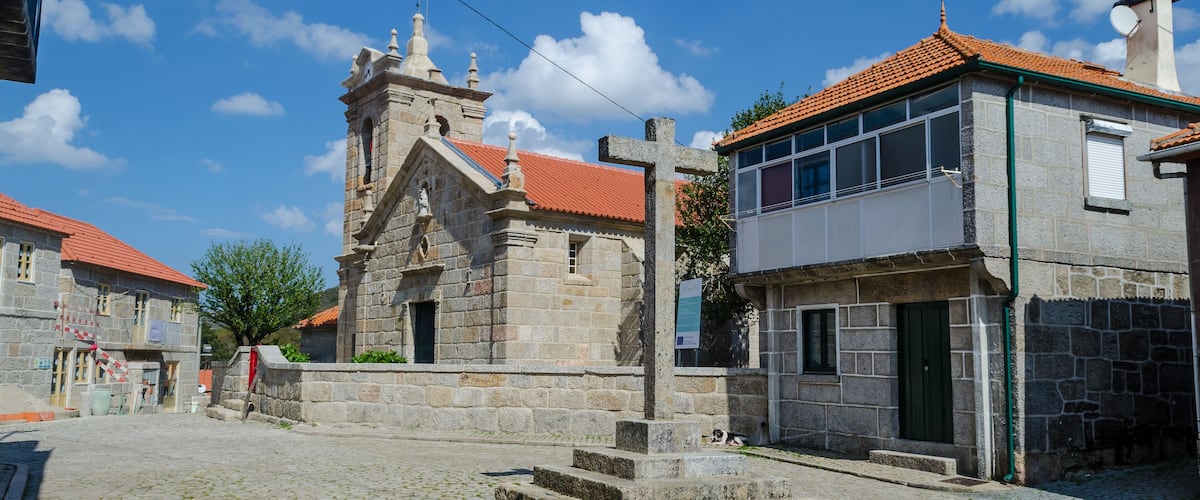 A cobblestone street with a stone church and a modern building with a red roof.