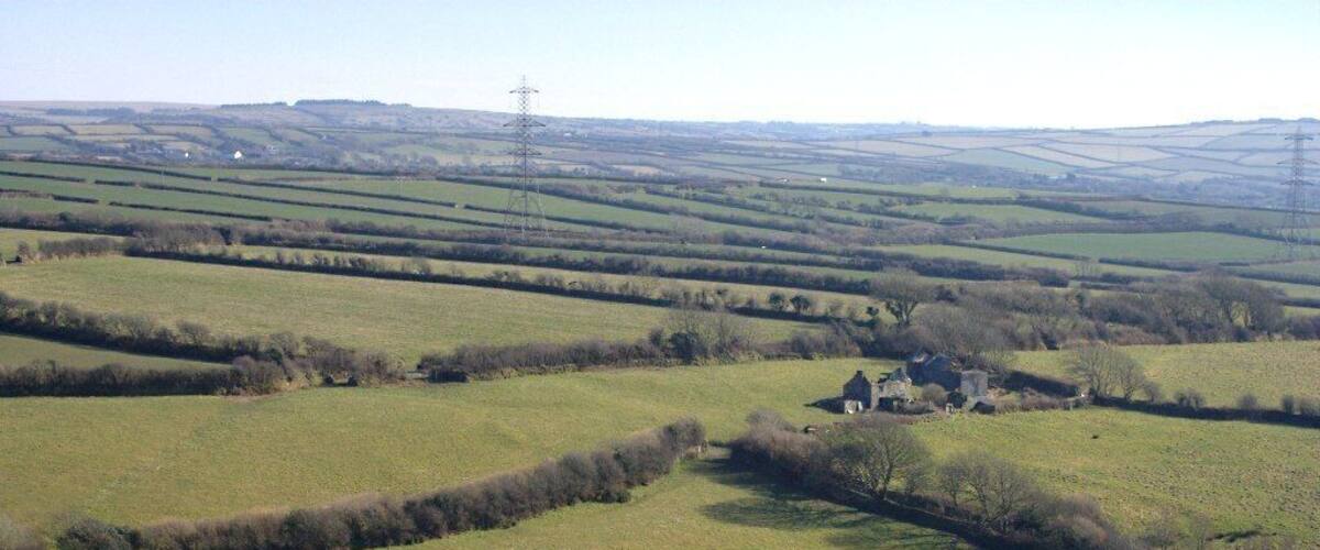 Rolling green fields, a small house, and distant power lines.
