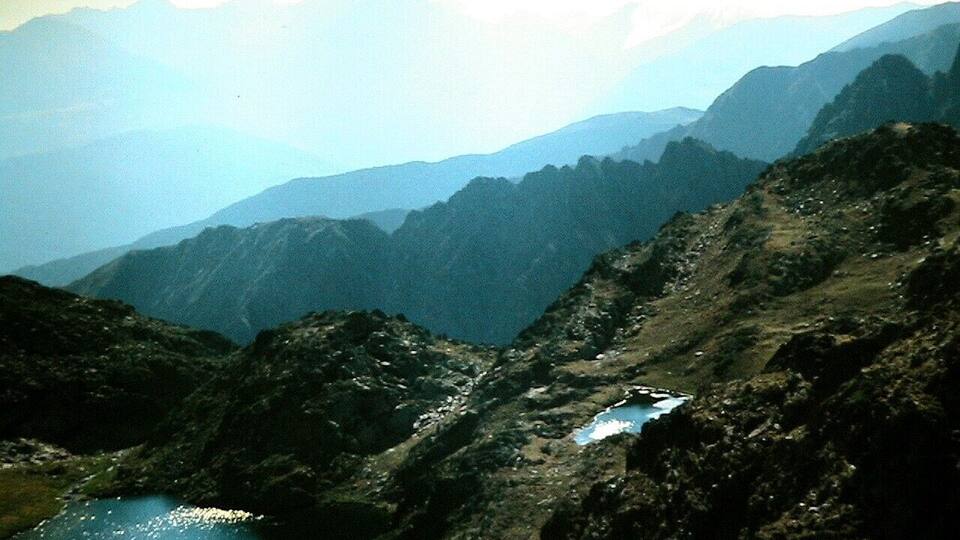 A mountainous landscape with a small lake and a rocky path.