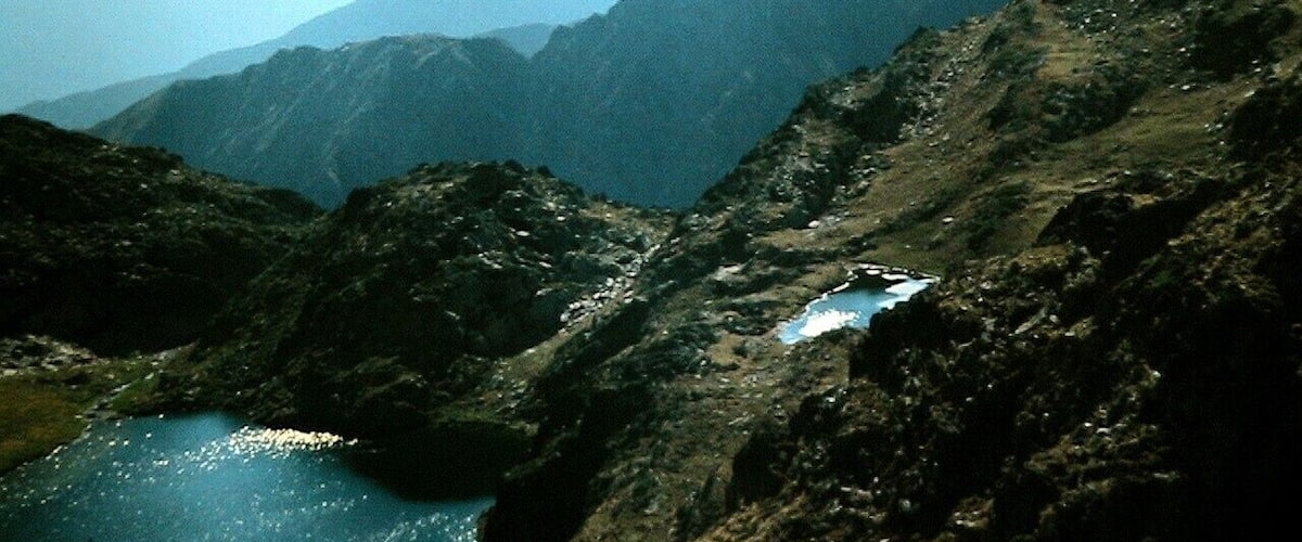 A mountainous landscape with a small lake and a rocky path.