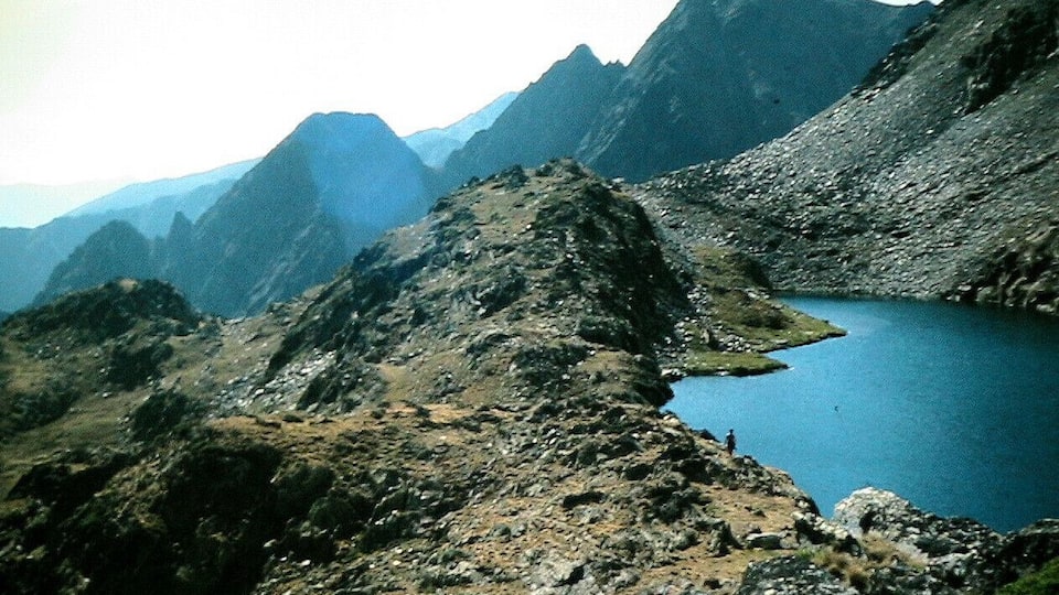 A mountainous landscape with a clear blue lake surrounded by rugged terrain.