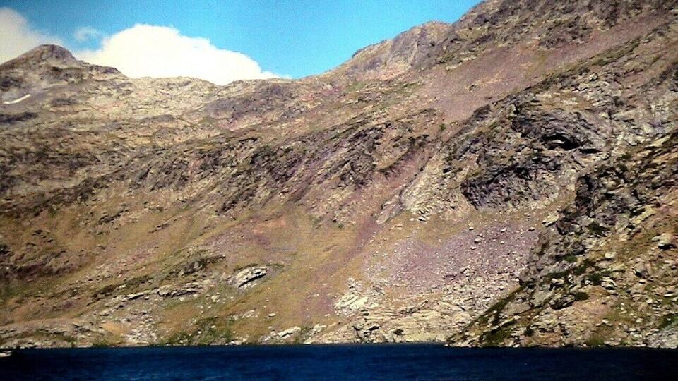 A mountainous landscape with rocky terrain and a body of water at the base.