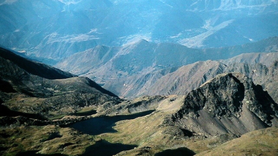 A mountainous landscape with a valley and a lake.