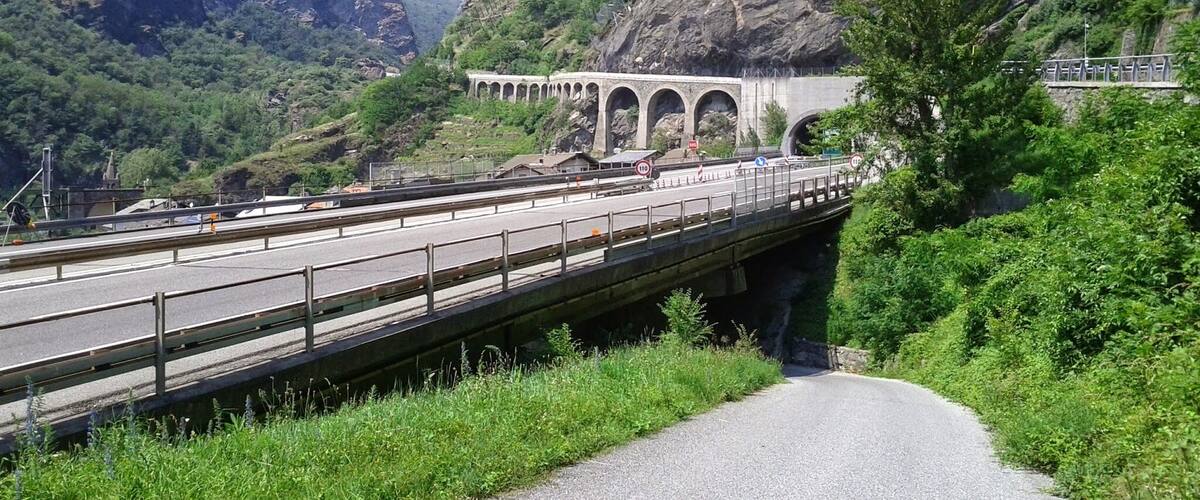 A bridge over a river with mountains in the background.