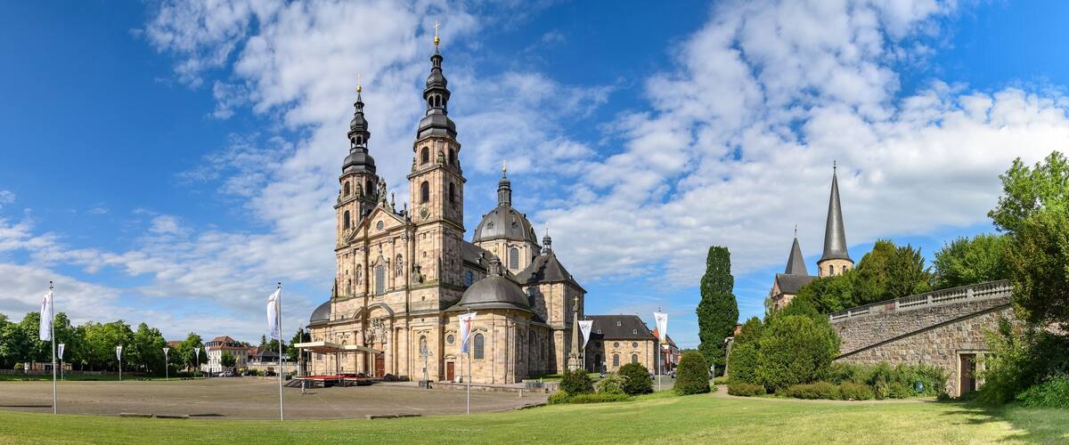 A historic church with multiple spires and domes, surrounded by a well-maintained lawn and trees.