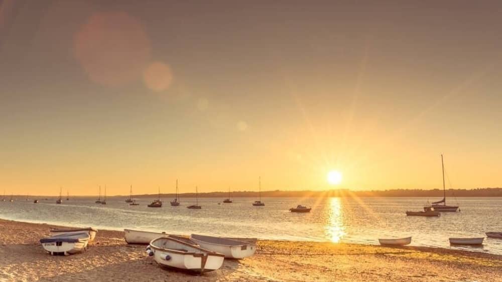 A beach with boats at sunset.