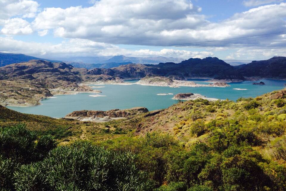 A mountainous landscape with a large body of water surrounded by rocky terrain and sparse vegetation.