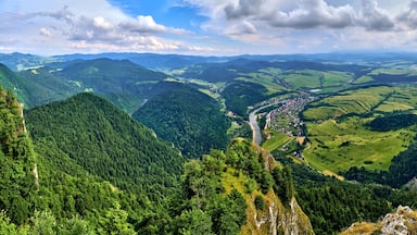 Um vale com um rio, cercado por montanhas arborizadas e uma pequena cidade.