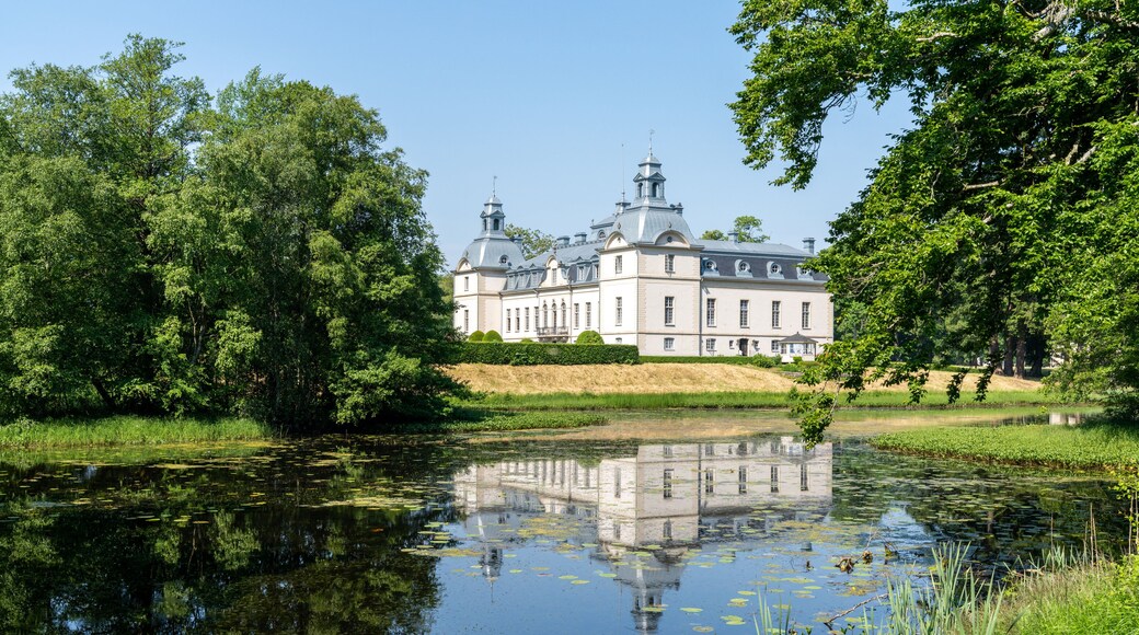picturesque Kronovall Castle and gardens reflected in a pond in the foreground on a summer dday under a blue sky