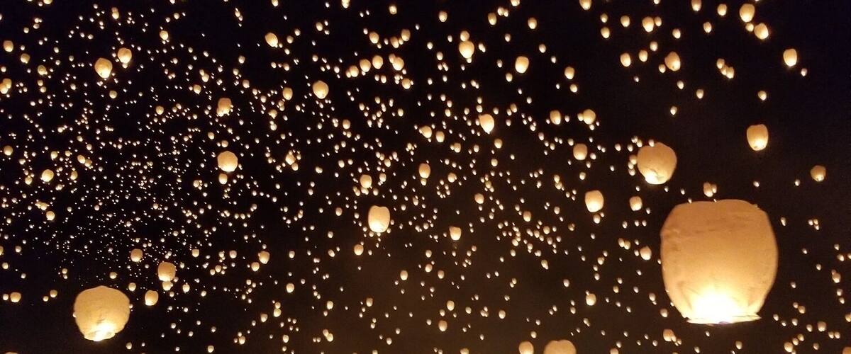 A crowd releasing sky lanterns at night.