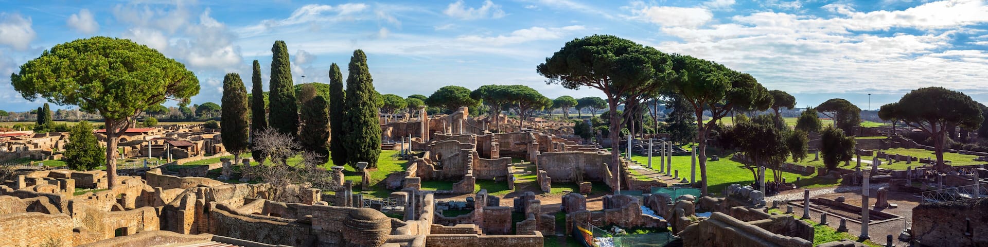 Ancient ruins with large trees and a clear sky.