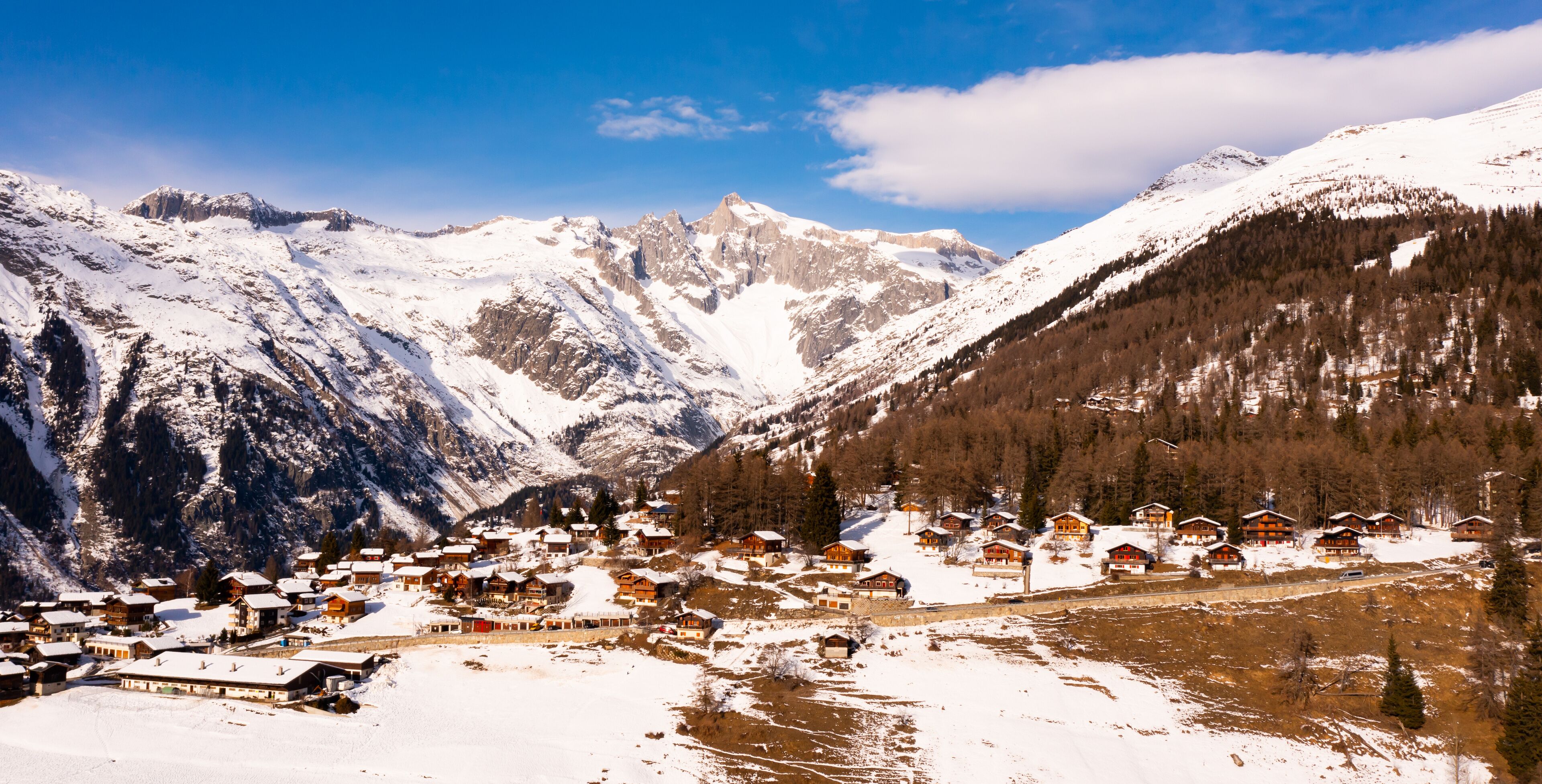 Townscape of Bellwald, Switzerland. View of residential buildings, forest and mountains.