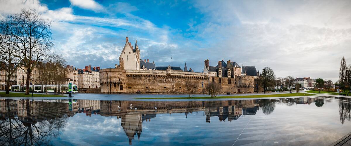 A historic castle with a moat and a clear reflection in the water.