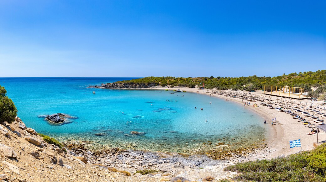 Crystal clear turquoise water in a Glystra beach. Cane umbrellas and sunbeds on an beach resort - vacation concept on Greece islands in Aegean and Mediterranean sea. Near Lindos at east Rhodes. Greece