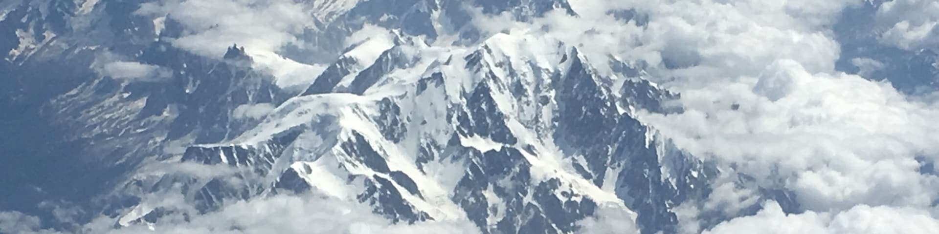 Snow-covered mountain peaks with clouds below.