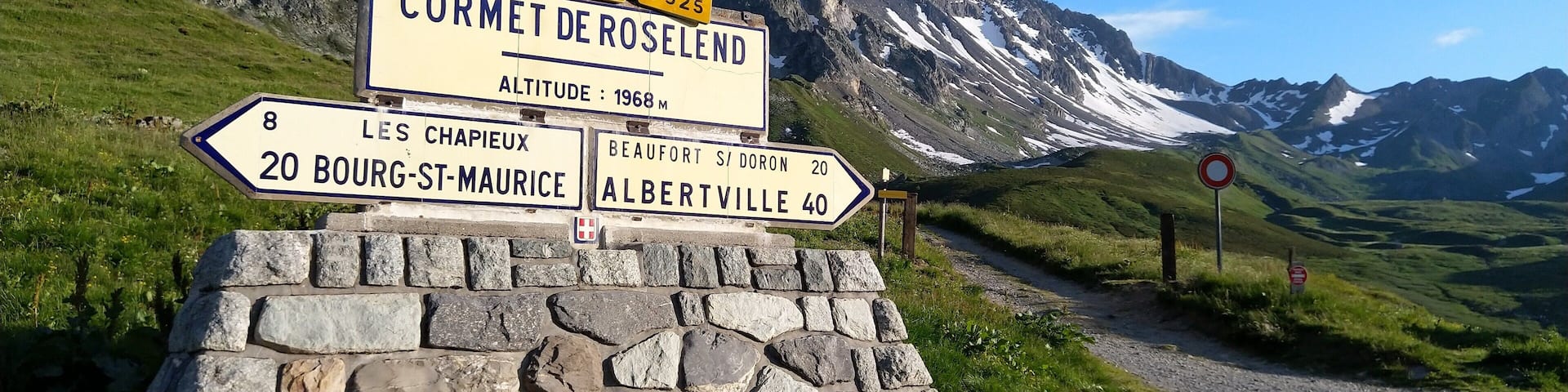 A mountain road sign with directions to Cormet de Roselend, Les Chapieux, Bourg-St-Maurice, Albertville, and Beaufort.