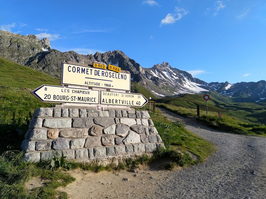 A mountain road sign with directions to Cormet de Roselend, Les Chapieux, Bourg-St-Maurice, Albertville, and Beaufort.
