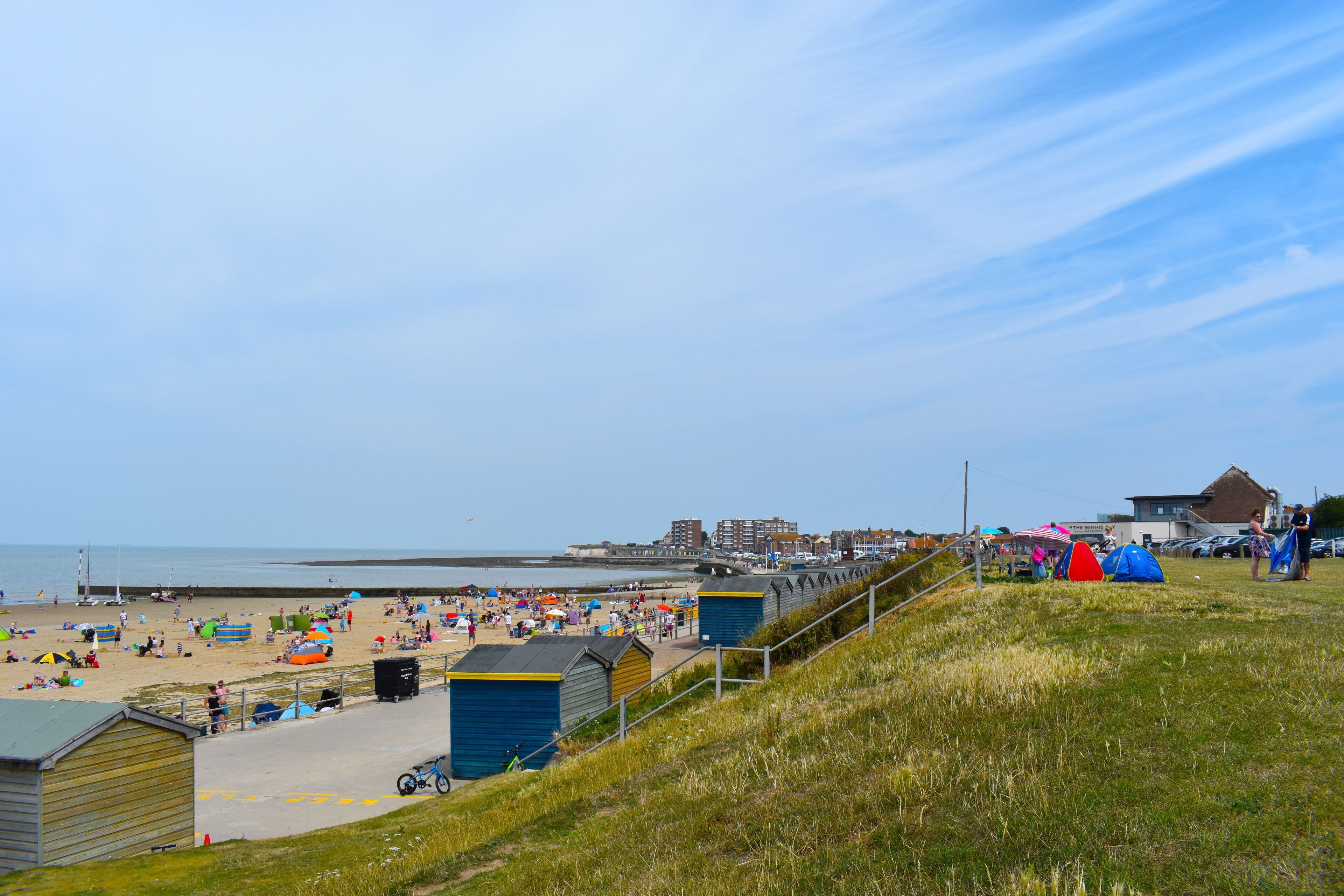A beach with people, tents, and buildings.