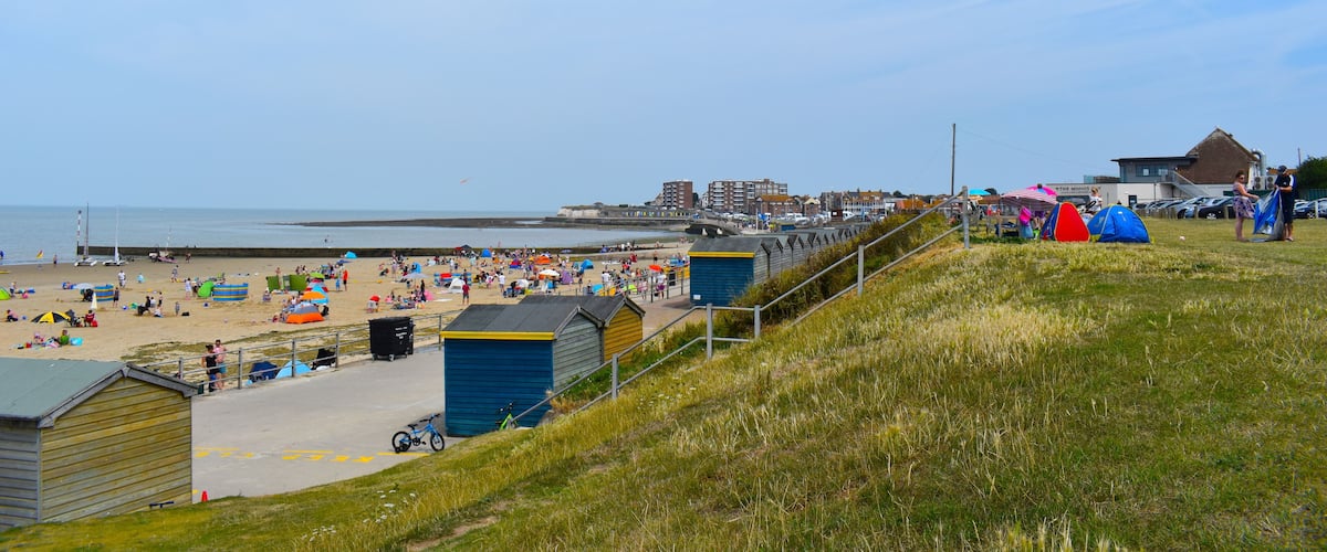 A beach with people, tents, and buildings.
