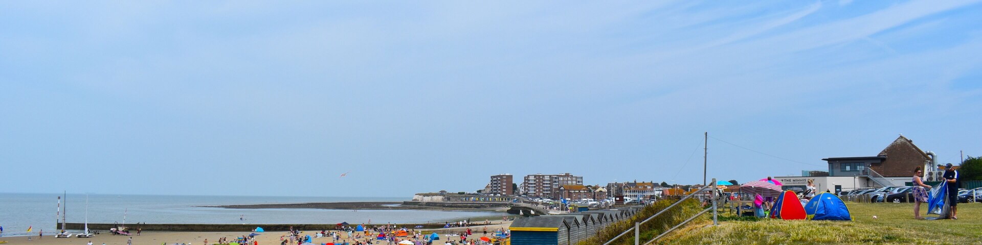 A beach with people, tents, and buildings.