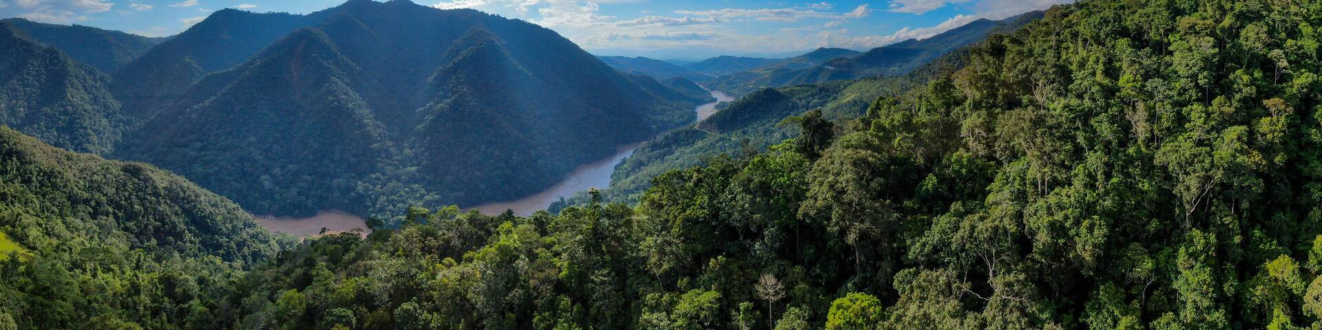 A mountainous landscape with a river flowing through a valley, surrounded by dense forests.