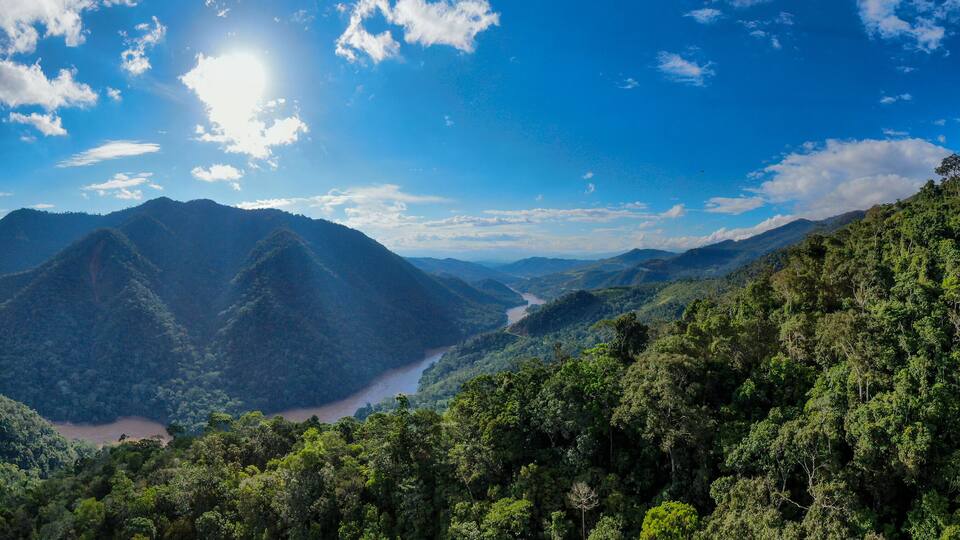 A mountainous landscape with a river flowing through a valley, surrounded by dense forests.