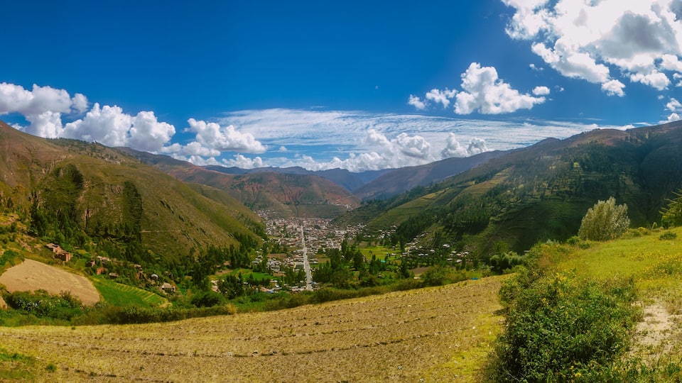 A mountainous landscape with a valley, green fields, and a small town.