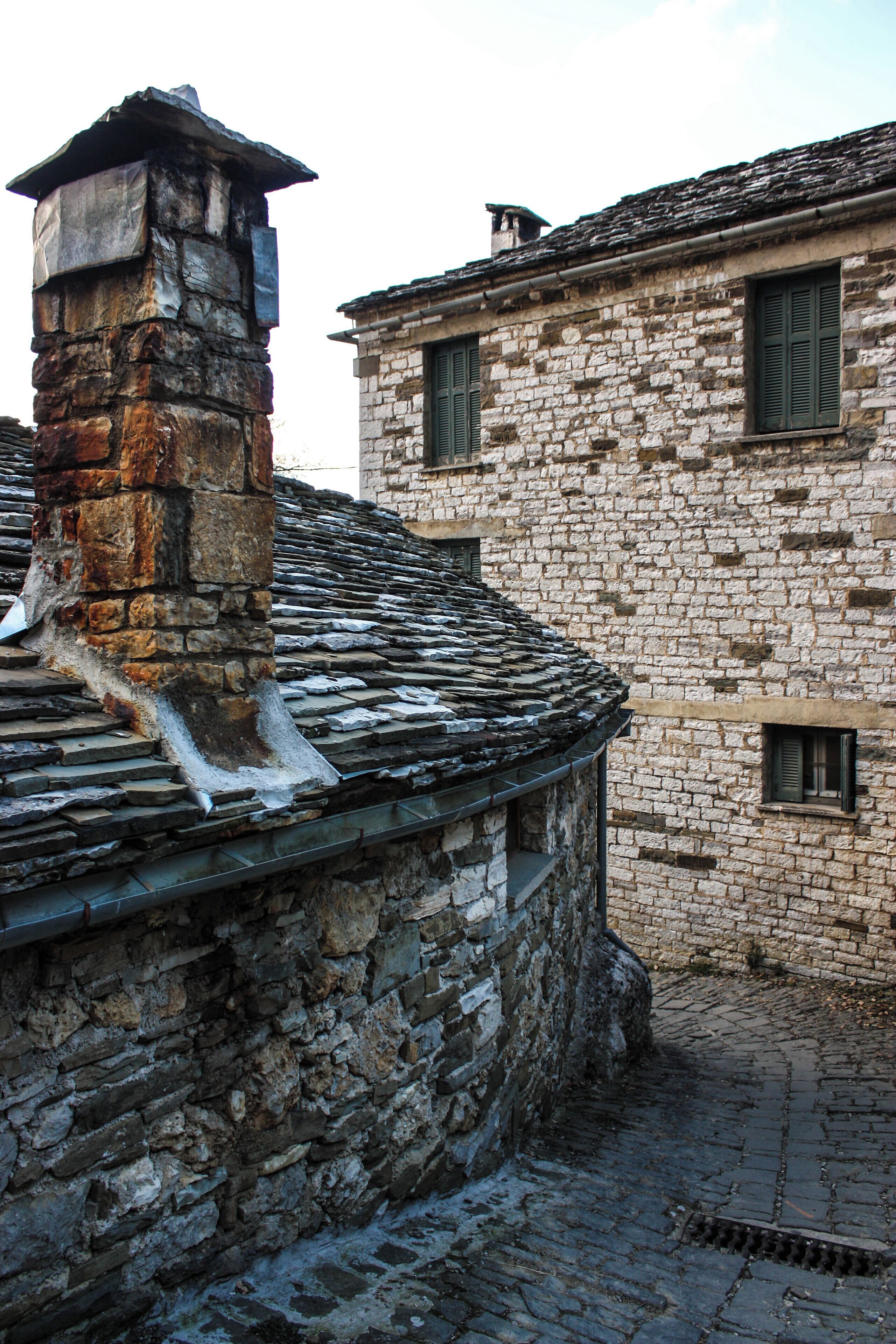 A stone building with a tiled roof and a chimney.