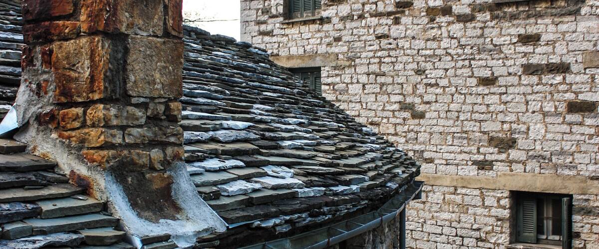 A stone building with a tiled roof and a chimney.