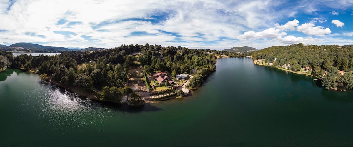 A lake surrounded by dense forests and a small island with houses.