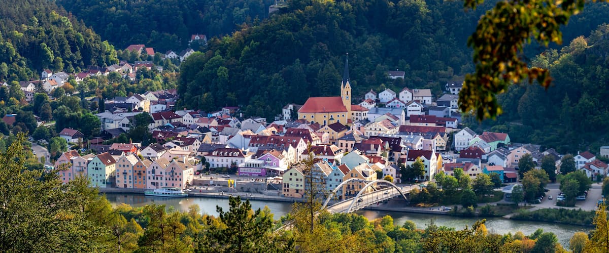 A town with colorful buildings, a river, and a bridge.