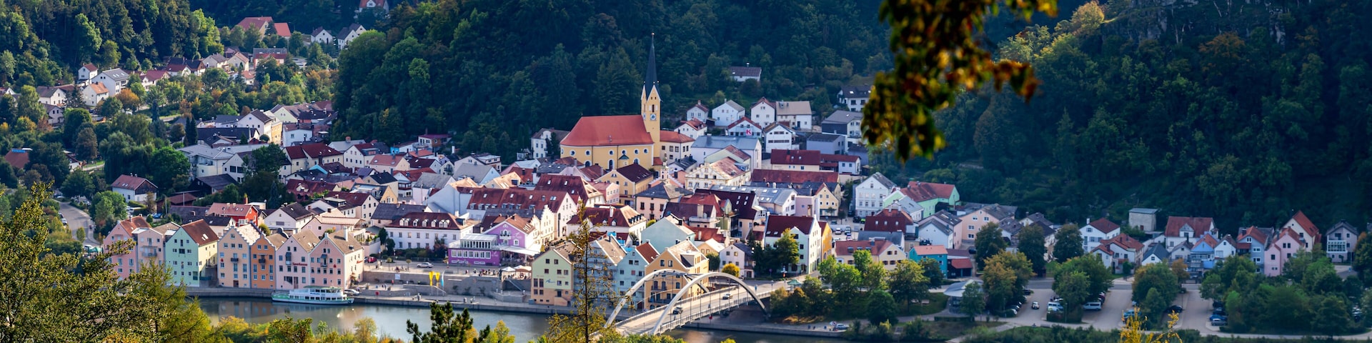 A town with colorful buildings, a river, and a bridge.