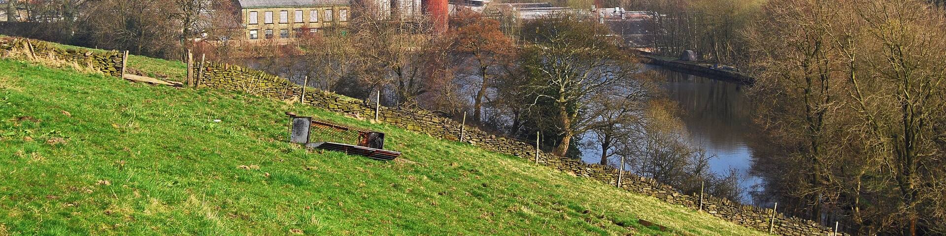 A red chimney, a river, and a green hill with buildings in the background.