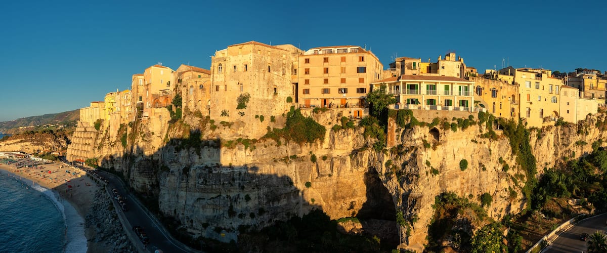 A coastal town built on a cliff with buildings overlooking the beach.