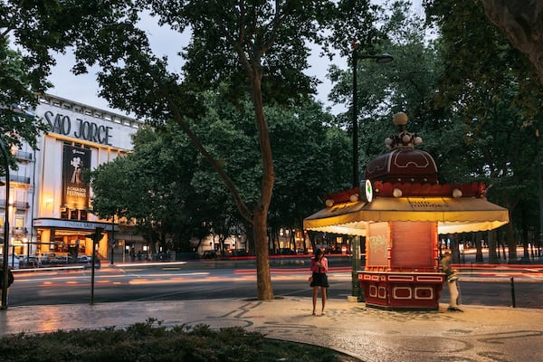 Ein Stadtplatz mit einem Brunnen, Bäumen und einem Gebäude, das 'SAO JOSE' ausweist.