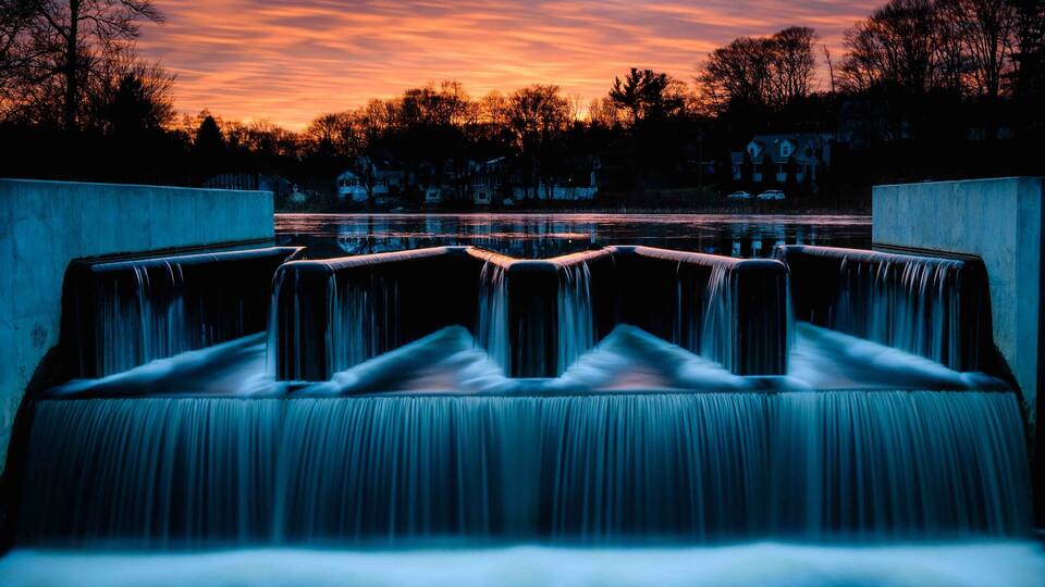 A waterfall with a sunset in the background.