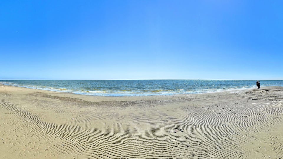 A sandy beach with gentle waves and a clear blue sky.