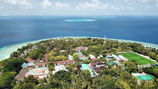 Maldives: Aerial View of Tropical Island Resort, with Private Beach, Palm Trees, Turquoise Sea, Blue Sky and Dramatic Clouds (Bandos Maldives, North Male Atoll, Indian Ocean) DJI Mavic Pro Drone