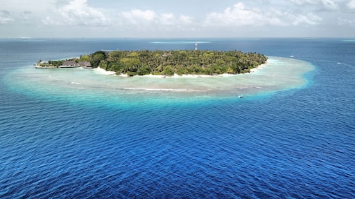 Maldives: Tropical Desert Island from Above, with White Sand Beach, Palm Trees, Turquoise Sea, Blue Sky and Dramatic Clouds (Bandos Maldives, North Male Atoll, Indian Ocean) DJI Mavic Pro Drone