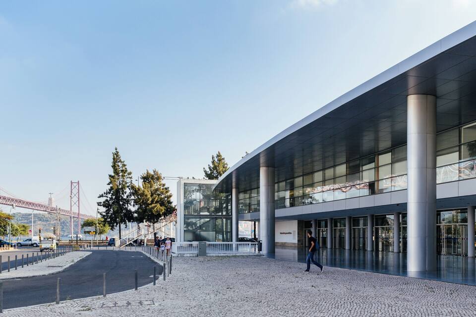A modern building with large glass windows and a paved plaza.