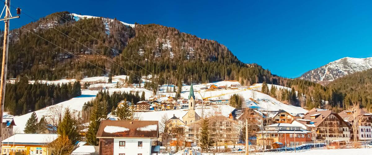 A snow-covered mountain town with buildings, a church, and a ski slope.