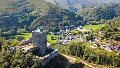 A medieval tower amidst a village surrounded by lush green hills.