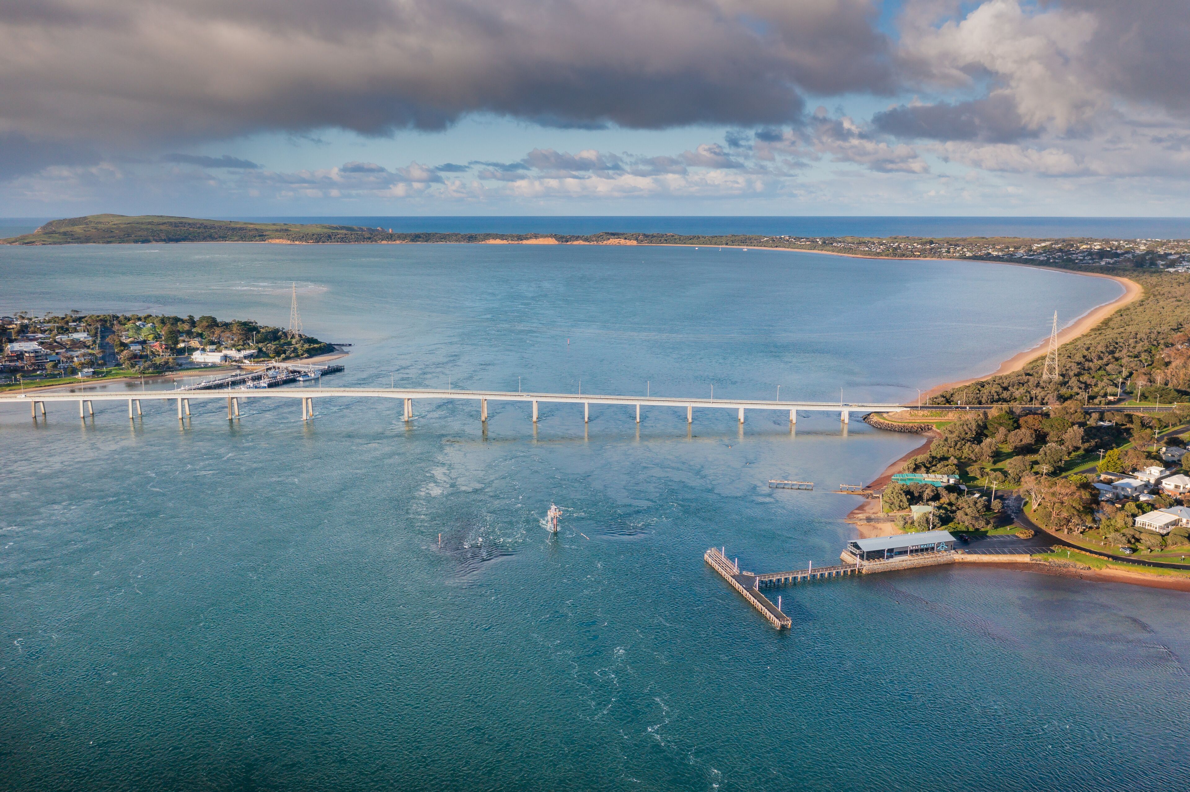 A coastal bridge, a pier, and a beach with houses.